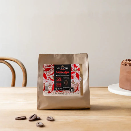 Sachet de fèves de chocolat noir Guanaja 70% de Valrhona pour la pâtisserie, format 1 kg, sur fond neutre.